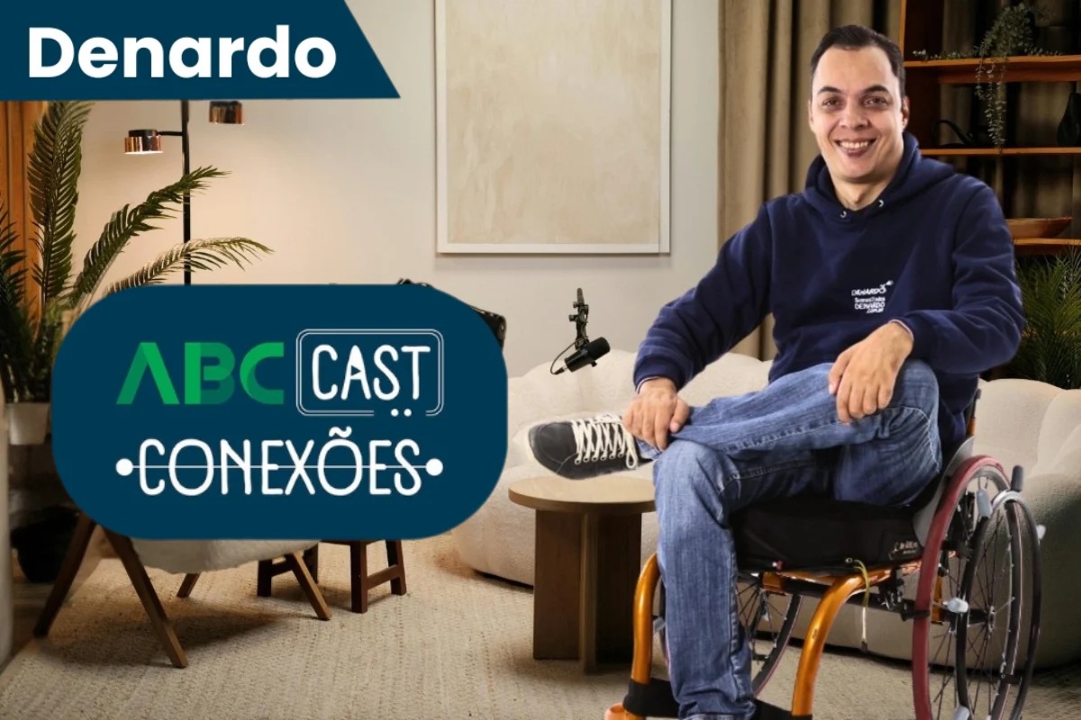 Ronaldo Denardo participa do ABC Cast Conexões sentado em sua cadeira de rodas em um estúdio moderno, com o logotipo do programa em destaque.